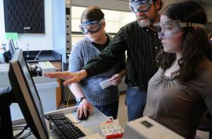 students wearing lab goggles looking at computer