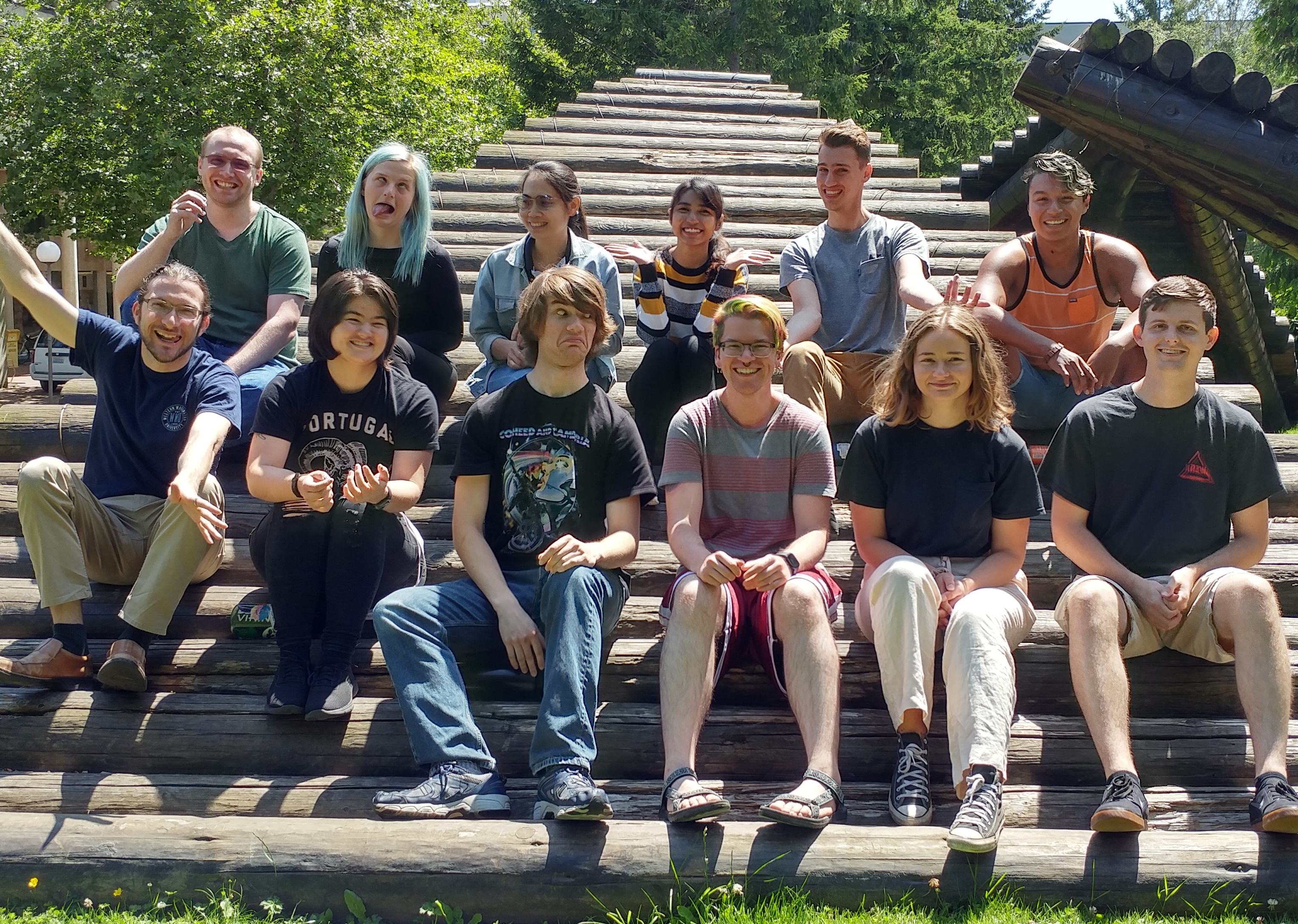 A group of students pose on a wooden sculpture Summer 2019