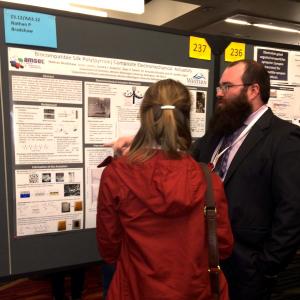 student presenting poster to audience member