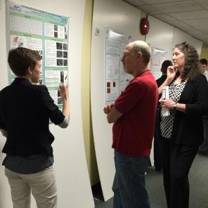 Student pointing at poster while people listen to presentation