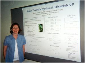 a woman poses beside a poster