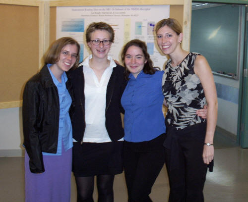 four women stand in a classroom, smiling at the camera