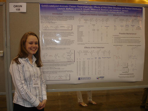 a student poses beside a poster
