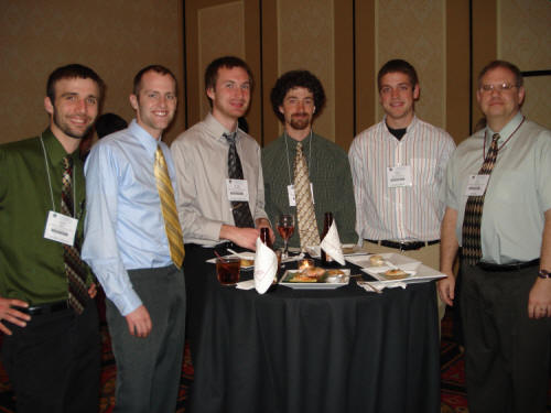a group of men pose beside a cocktail table