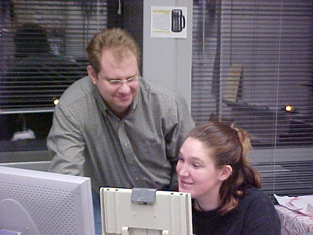 a man looks on as a women works on the computer