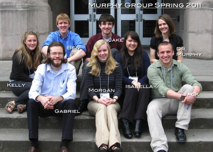 A group of students and Amanda Murphy sit on concrete steps, smiling at the camera. The photo is labeled "Murphy Group Spring 2011"