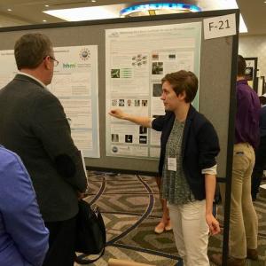 Student presenting poster to group of people at conference