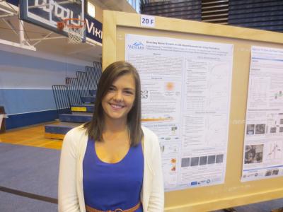Student stands in front of research poster
