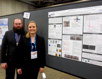 Two students standing in front of their poster at conference