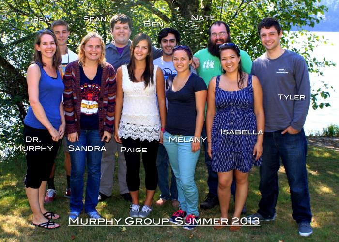 A group of students and Amanda Murphy stand in front of a tree, smiling at the camera. The photo is labeled "Murphy Group Summer 2013"