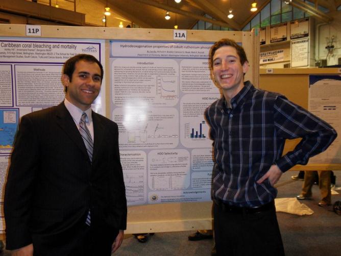 two students standing in front of posters at scholars week