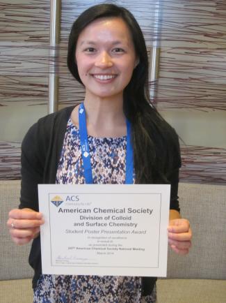Student standing with poster award